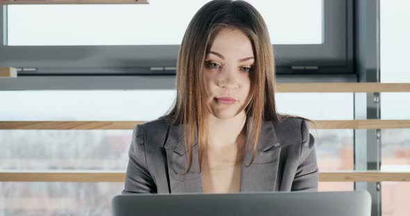 Concerned Woman Working on Laptop Computer and Looking Away Thinking Solving Problem at Office