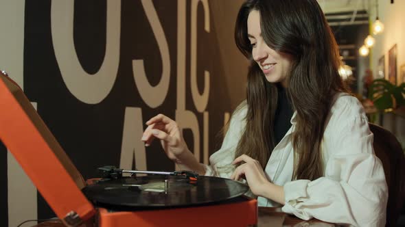 Young Woman with Old Record Player and Vinyl Discs at Home