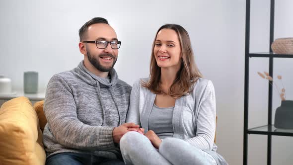 Happy Enamored Couple Hugging Posing Together on Couch Having Positive Emotion