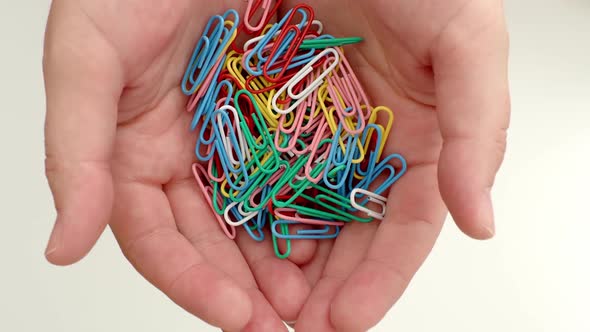 paper clips in hand on a white background, scattered on the table