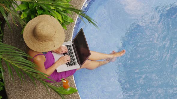 Woman sitting on edge of hot tub using laptop computer. Shot on RED EPIC for high quality 4K, UHD, U