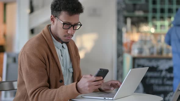 African Man Laptop Using Smartphone Cafe