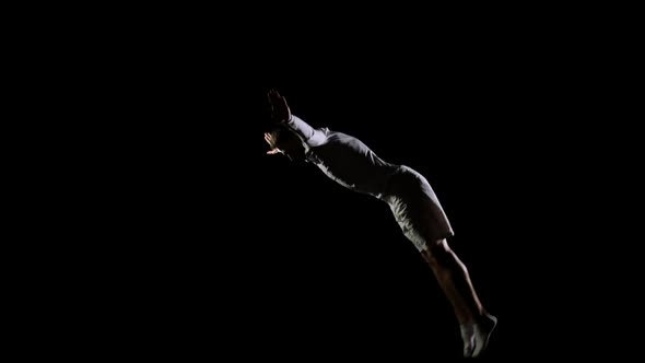 Jump Gymnast Men on a Black Background on a Trampoline. Freedom and Flight