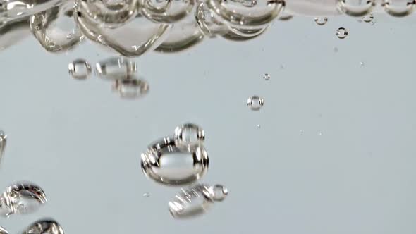 Macro Shot of Air Bubbles in Water Rising Up on Light Blue Background
