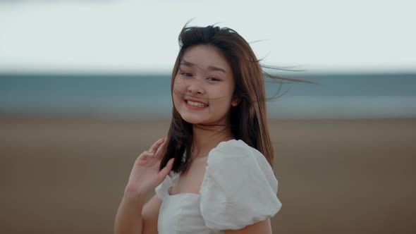A cute Asian girl is walking on the beach by the sea