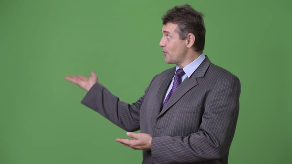 Mature Handsome Businessman Against Green Background