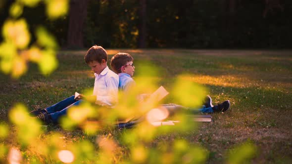 Children with Books and Schoolbags Do Home Task in Park