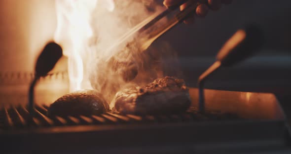 Close up of professional chef using fire grill to cook meat