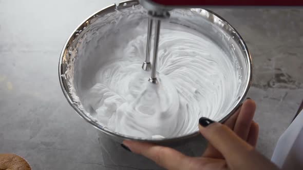 Woman Hands Mixing white Egg Cream in Bowl Using Motor Mixer