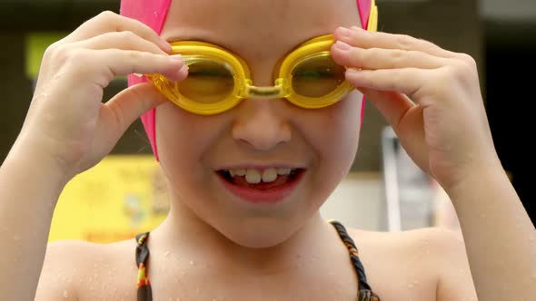 Cheerful Child Puts on Swimming Goggles for Swimming in the Pool