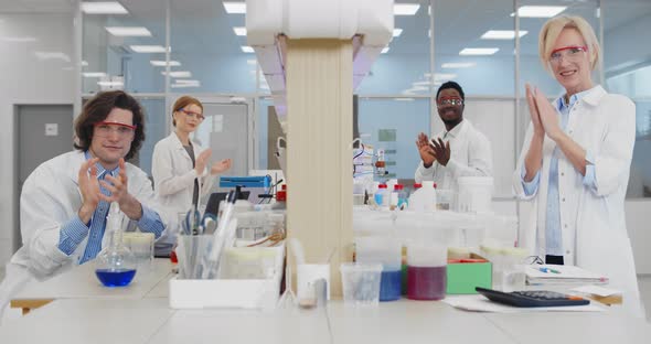 Multiethnic Group of Medical Researchers Applauding Together Smiling at Camera in Modern Laboratory