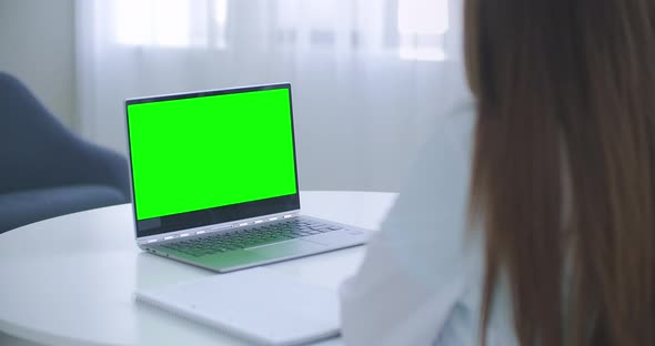 Woman Doctor Is Consulting Online, Laptop with Green Screen on Table, Chroma Key Concept