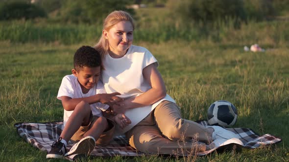 Mother and Kid a Boy on a Picnic in a Field