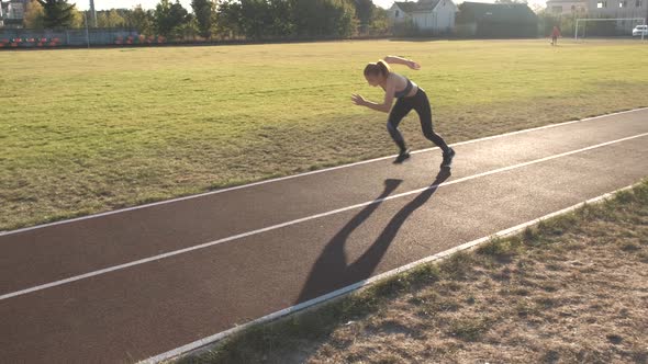 Young woman running on stadium run track outdoors.