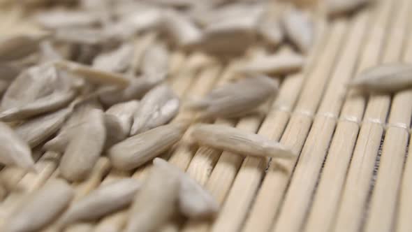 Falling peeled uncooked sunflower kernels in slow motion onto the bamboo mat surface