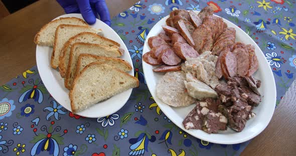 Buffet selection of venison sausages on a wooden board with lunch platter of sliced meat and cheese