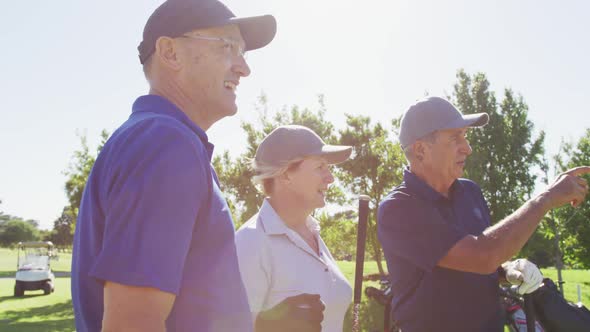 Senior people talking to each other while practicing golf on the golf course on a bright sunny day