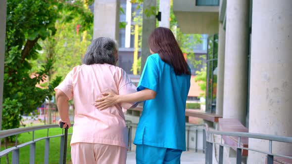 Doctor help old elderly Asian woman uses a walker and walking for physical therapy in the hospital.