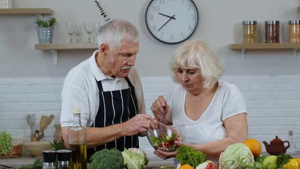 Senior Woman and Man Feeding Each Other with Fresh Raw Vegetable Salad. Eco Food Eating Diet