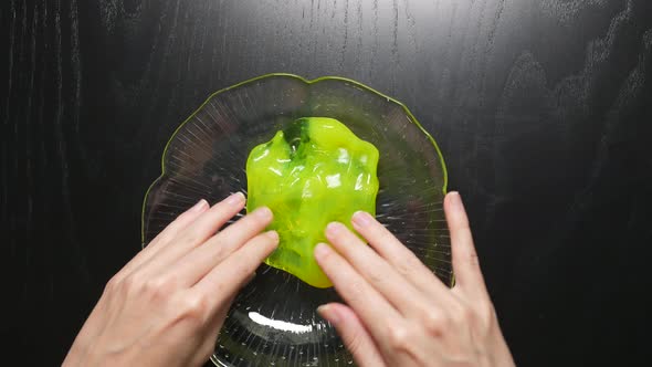 Fiddling with a yellow slime in a glass bowl