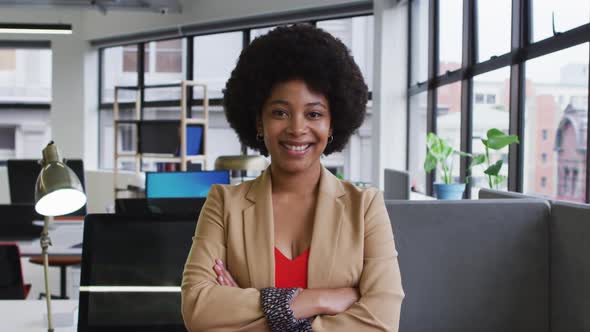 Portrait of mixed race businesswoman sitting looking at camera and smiling in office