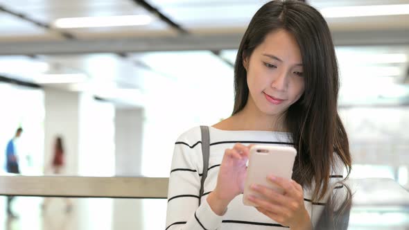 Woman using mobile phone in train station