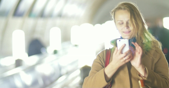 Woman With Smart Phone On Subway Escalator