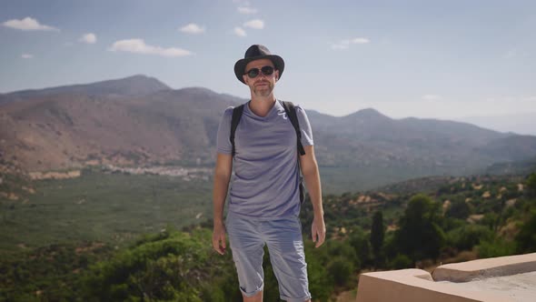 Happy Tourist with a Backpack Enjoying a Beautiful View of the Valley and Mountains