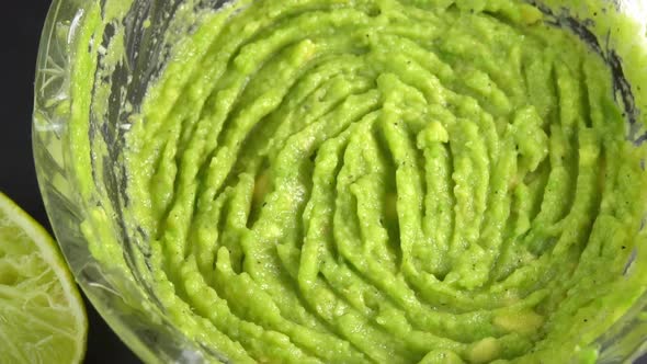Guacamole dip rotating in glass bowl background. Cooking healthy food. Making avocado dip