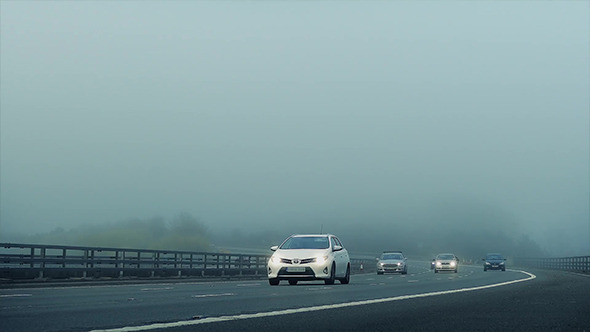 Cars Pass On Highway In The Mist