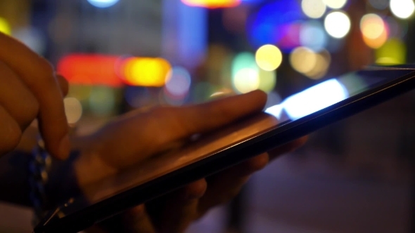 Hands Using Digital Tablet Against Night City