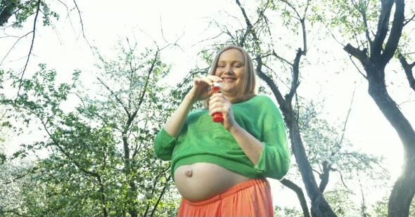 Pregnant Woman Blowing Soap Bubbles Outdoor