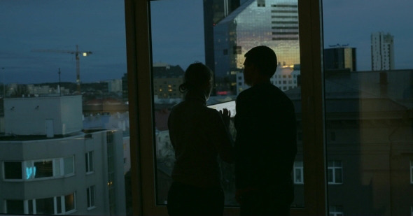 Couple Using Pad And Enjoying View Of Evening City alt