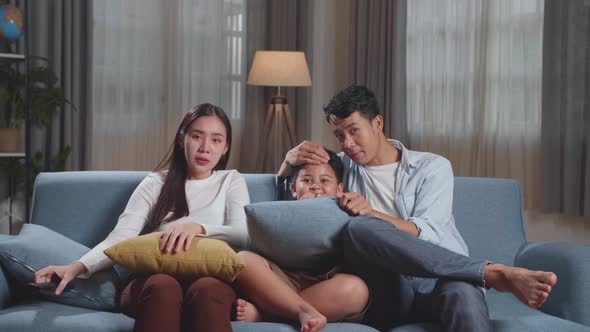 Asian Family, Leisure And People Concept, Father, Mother And Son Watching Scary Movie On Tv At Home