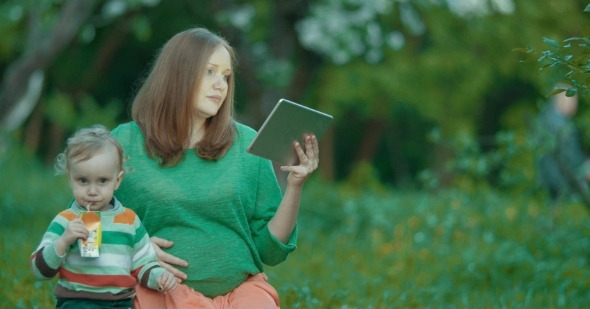 Pregnant Mother And Son Using Pad In The Park alt