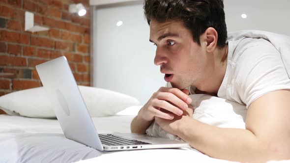 Man in Bed in Shock by Results on Laptop, Wondering