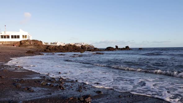 Small foamy waves coming to the rocky beach during the evening Las Galletes, Tenerife