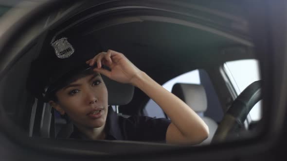 Asian Police Officer Adjusting Her Uniform Cap Looking Into Rearview Mirror