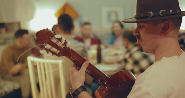 Young Male Guitar Player with a Hat Playing for His Friends