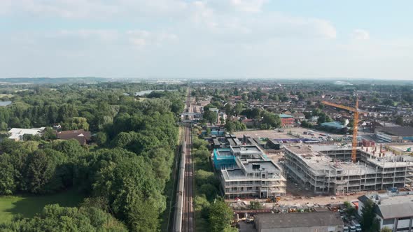 Low follow drone shot over British rail train entering Cheshunt station north London