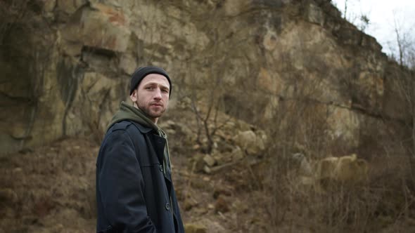 Stylish Young Guy Standing In Nature. Behind Him Is Rock.