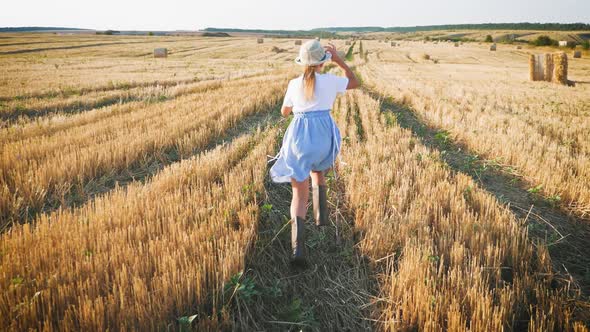 Little Girl in a Field with Haystack Run at Sunset in the Countryside.