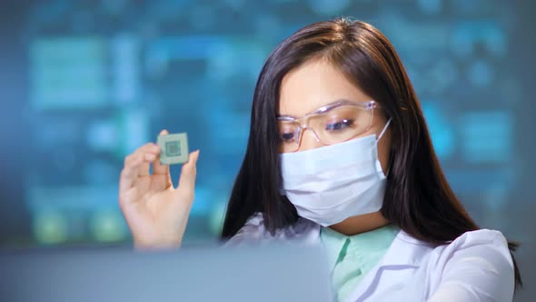 Female Asian Engineer Working with Microchip at Modern Electronic Manufacturing Lab Using Computer