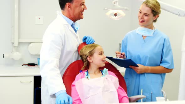 Dentist interacting with nurse while treating to girl