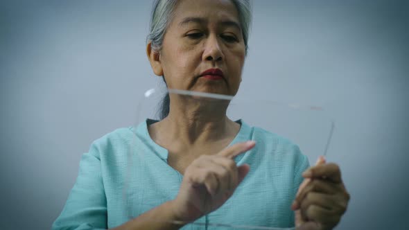 Active Senior Asian Woman Using a Futuristic Tablet 