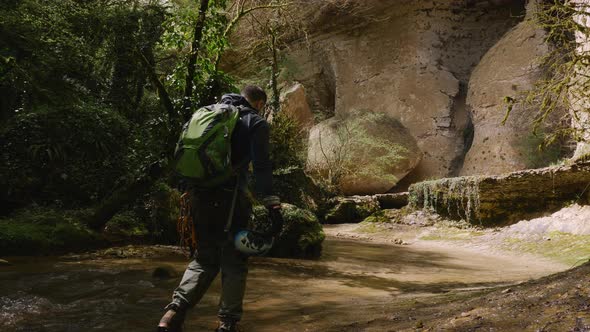 Male Traveler with Backpack Walking Along the River or Stream in a Tropical Cave