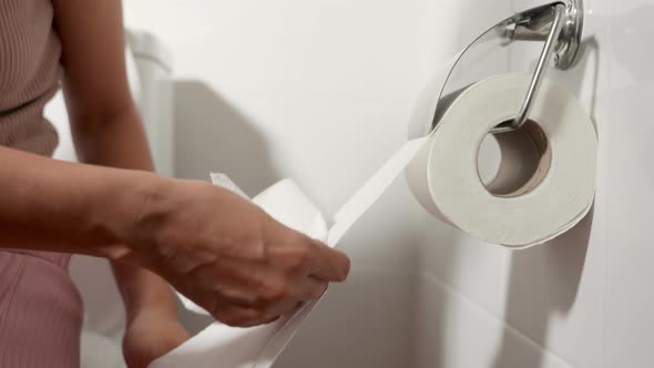 Closeup hand pulling toilet paper roll in holder for wipe