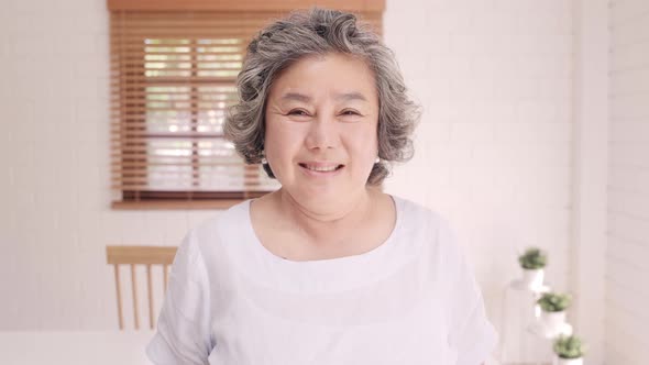 Asian elderly woman feeling happy smiling and looking to camera while relax on the sofa.