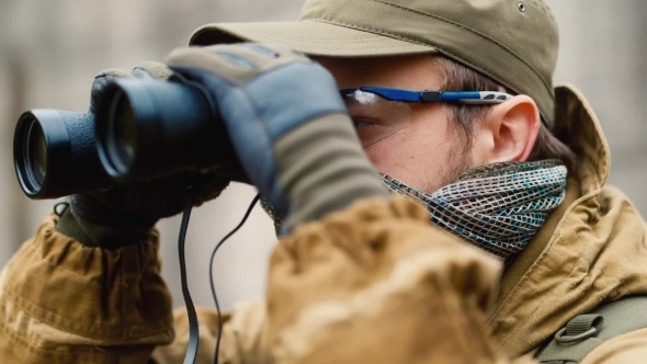 Man In Camouflage Looking Through Binoculars