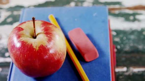 Apple, pencil and eraser on book stack